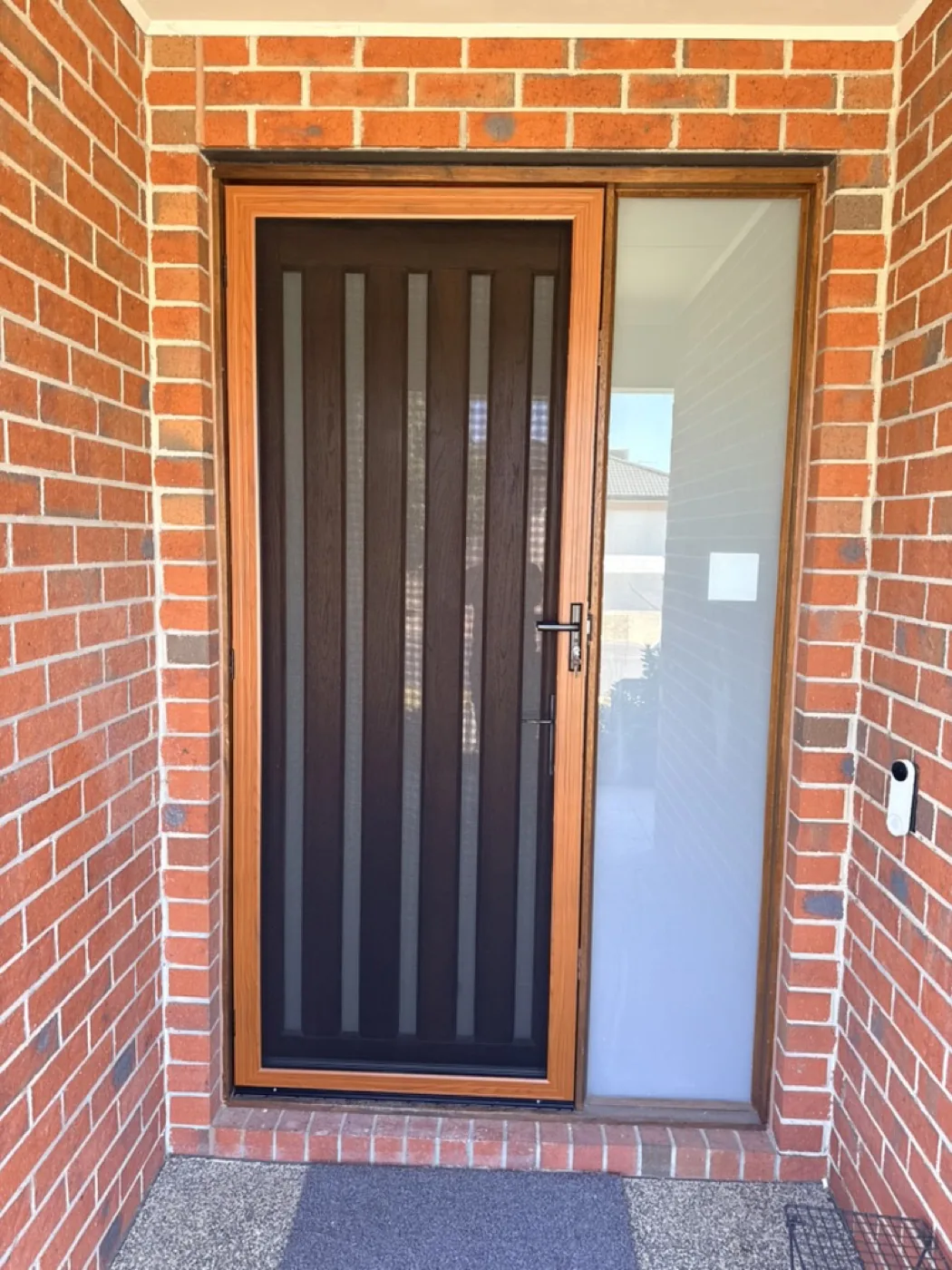 Timber-look security door with dark slat inserts and frosted sidelight