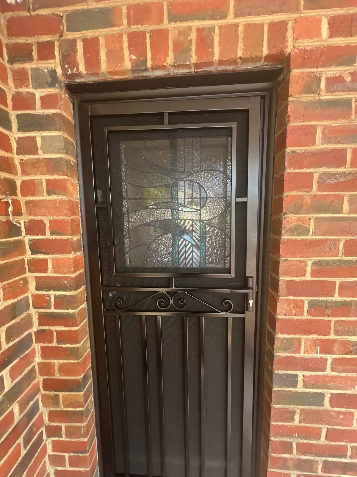 Classic decorative steel security door on a heritage brick home