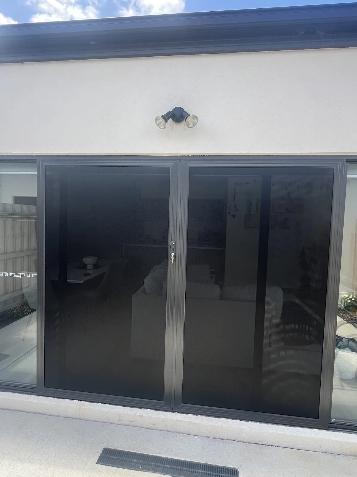 Modern black sliding security doors on rendered home