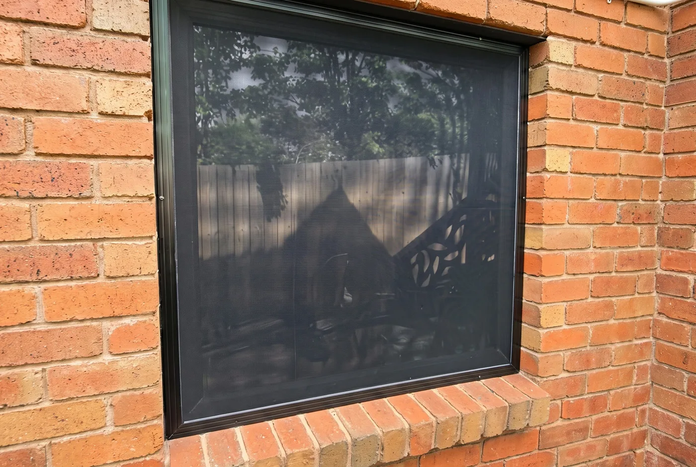 Black security mesh window screen installed on a red brick Melbourne home